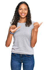 Young african american girl wearing casual clothes pointing to the back behind with hand and thumbs up, smiling confident
