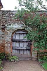 Old wooden gate in brick archway, Warwickshire England
