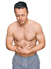 Fototapeta premium Handsome young man wearing swimwear shirtless with hand on stomach because indigestion, painful illness feeling unwell. ache concept.