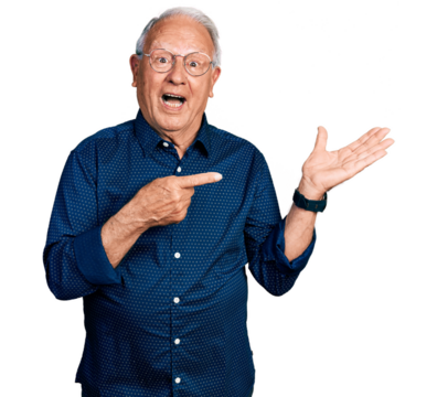 Senior man with grey hair wearing casual shirt and glasses amazed and smiling to the camera while presenting with hand and pointing with finger.