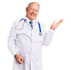 Senior handsome grey-haired man wearing doctor coat and stethoscope smiling cheerful presenting and pointing with palm of hand looking at the camera.