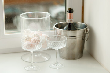 A bottle of champagne in a bucket on the window. Bachelorette party. Birthday. Pink marshmallows and festive glasses