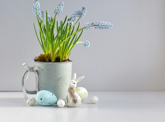 Easter composition with white rabbit, eggs and light blue muscari flowers in cup. Easter still life - 767840323