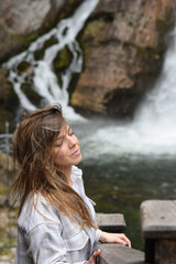 Relaxed smiling woman enjoying travelling next to the waterfalls 