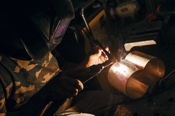  Male in face mask welds with argon welding. Industrial welder worker welding using argon machine,...