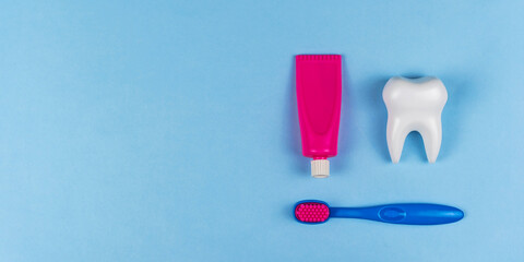 The health of children's teeth. White healthy tooth and baby toothpaste and brush on a blue background. A concept for a dental clinic, a pediatric dentist, oral hygiene, oral care. Copyspace for text