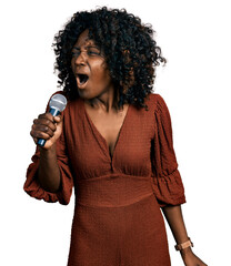 African woman with curly hair singing song using microphone angry and mad screaming frustrated and...
