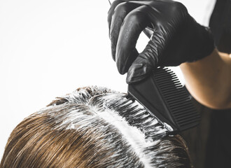 Hairdresser is applying bleaching powder on woman's hair - obrazy, fototapety, plakaty