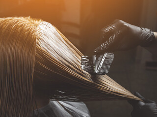 Hairdresser is applying bleaching powder on woman's hair