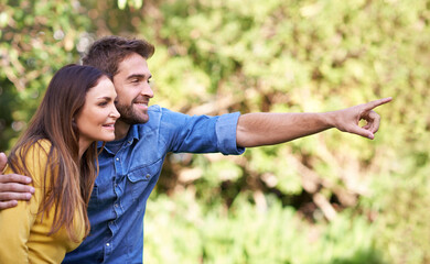 Happy couple, woman and man pointing in trees or nature for bonding, dating and relationship with smile. People, love and romantic in park or outdoor with joy, excited and commitment in marriage