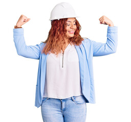 Young latin woman wearing architect hardhat showing arms muscles smiling proud. fitness concept.