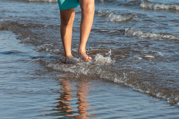 Feet of a young person walking along the seashore.