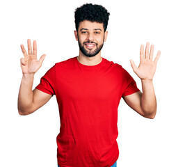 Young arab man with beard wearing casual red t shirt showing and pointing up with fingers number nine while smiling confident and happy.