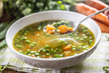 Healthy vegetable soup from fresh spring vegetables. A close-up view of a spoon full of hot soup - 767855950