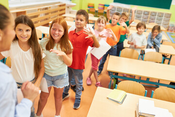 Happy schoolkids waving at female teacher