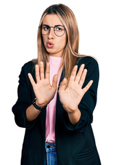 Hispanic young woman wearing business jacket and glasses moving away hands palms showing refusal and denial with afraid and disgusting expression. stop and forbidden.