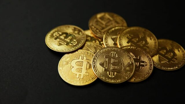 Close up of a pile of bitcoins golden coins on a black background, camera panning movement. Bullish BTC, cryptocurrency, 2p2 exchange and blockchain concept