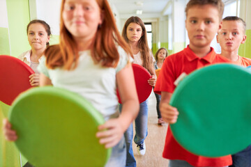School children walking in hallway with cushions