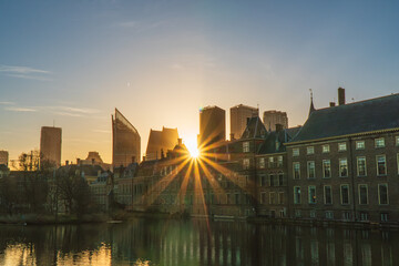 Sun rays piercing through the Binnenhof Castle, Mauritshuis museum and the modern skyline of The Hague, the Netherland. Clear sky, spring.
