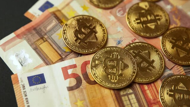 Close up of several gold bitcoin coins on 50 euro bills, camera panning movement. Bullish BTC, cryptocurrency, 2p2 exchange and blockchain concept