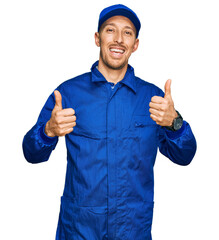 Bald man with beard wearing builder jumpsuit uniform success sign doing positive gesture with hand, thumbs up smiling and happy. cheerful expression and winner gesture.