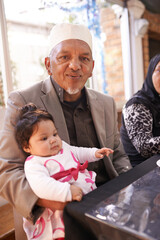 Muslim, grandfather and portrait with baby in family home and relax on Eid holiday or party with...