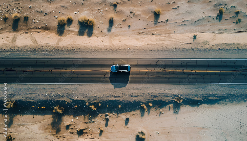 Wall mural car moves along an asphalt road in the desert top view