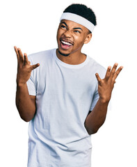 Naklejka premium Young african american man wearing sportswear crazy and mad shouting and yelling with aggressive expression and arms raised. frustration concept.