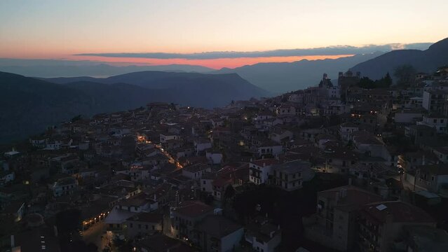 This aerial footage was made with a drone over a greek village called Arachova, with the main sightsee place, the “Clock Tower of Arachova” high in mountains after the sunset, blue hour, in March 2024