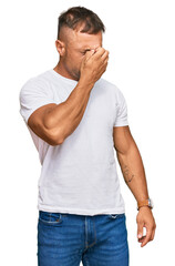 Handsome muscle man wearing casual white tshirt tired rubbing nose and eyes feeling fatigue and...