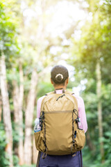 Back view of woman hiking with backpack outdoors