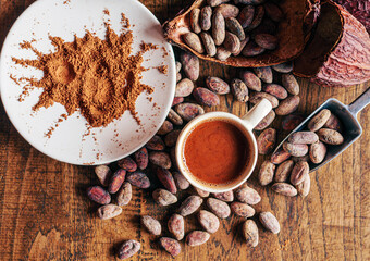 Top view of hot chocolate drink,cocoa drink and natural cocoa powder with brown cocoa beans and dry cacao pod  on a vintage wooden table.