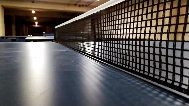 Table tennis table and table tennis net in close-up view with net mesh details while players playing table tennis and ping pong as leisure activity and professional sport indoor competition activity