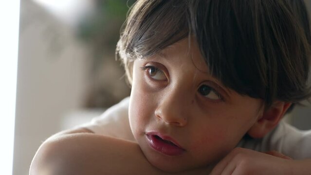 One thoughtful pensive young 5 year old bout in deep mental reflection. Introspective male caucasian kid daydreaming