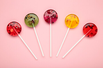 Colorful sweet lollipops with berries on pink background.
