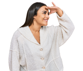 Young brunette woman wearing casual clothes very happy and smiling looking far away with hand over head. searching concept.
