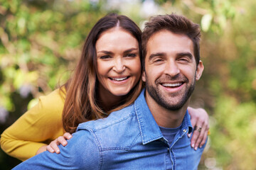 Portrait, nature and happy couple with piggyback in park for bonding, dating and relationship outdoor. People, love and romantic in backyard with smile or joy, excited and commitment in marriage