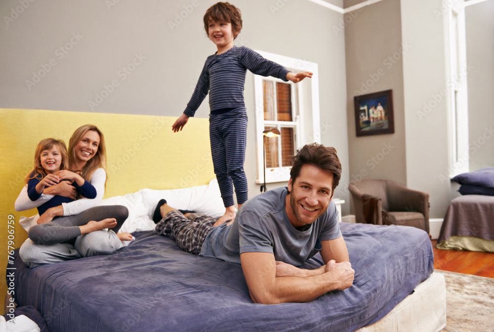 Wall mural Home, parents and kids fun on bed with love, support and bonding together with a smile. Happy, family and children with mom in the morning in the bedroom play with sibling in a house with parenting