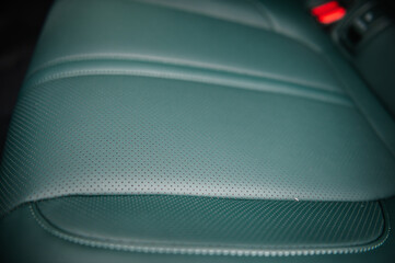 Part of green leather car seat. Luxury car inside. Interior of prestige modern electric car. Supercar design detail. Concept of future. Seat with perforated leather cockpit closeup.