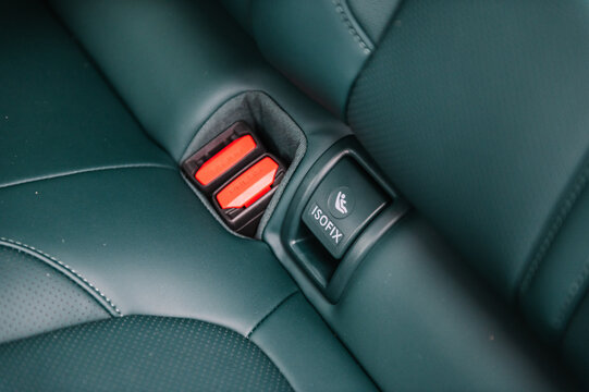 Fastening child seat with isofix system. Installing ISOFIX baby and car seat for maximum safety. Part of green perforated leather car seat. Luxury car inside. Interior of prestige modern electric car.