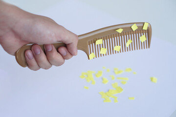 Hand holds comb and small pieces of paper. Equipment, prepared to do experiment about static...