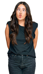 Obraz premium Beautiful brunette young woman wearing black shirt making fish face with lips, crazy and comical gesture. funny expression.