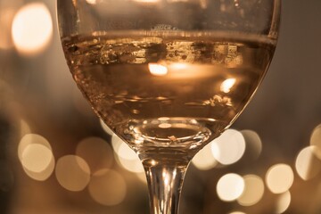 a glass of white wine with bubbles floating around it and the lights of boke