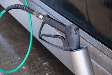 A man washes off the foam while washing the car. A vehicle is engulfed in soapy foam during a car wash, covering the tires, wheels, hood, and entire exterior of the car. Self-service car wash