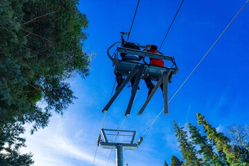 A sky lift with two skiers on it with a blue sky in the background