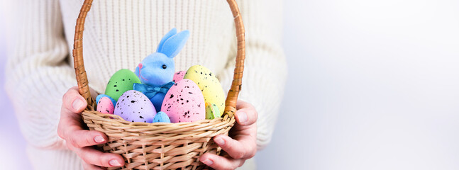Woman holds decorative Easter Eggs and the Easter Bunny in a wicker basket. Easter decor. Banner....