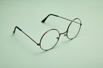 Open metal rimmed spectacles isolated on light-green. - 767918596