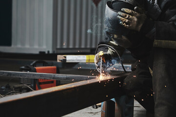 Male in face mask welds with welding