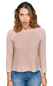 Beautiful young caucasian woman wearing casual sweater in shock face, looking skeptical and sarcastic, surprised with open mouth