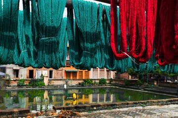 Selection of brightly colored garments hang suspended over a tranquil body of water